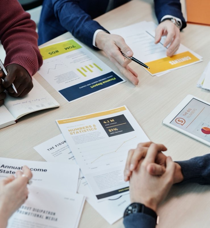 Consultants reviewing printed financial reports across a meeting table