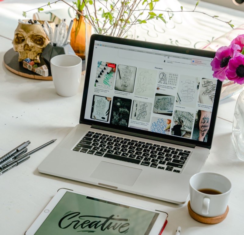 Designer's desk with lettering work open on a laptop and a tablet