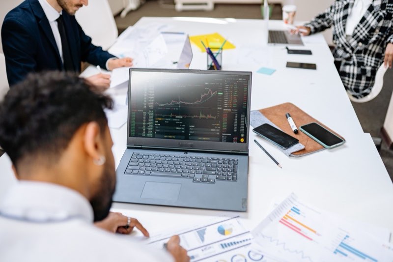 Traders following market data on a laptop in an open-plan office