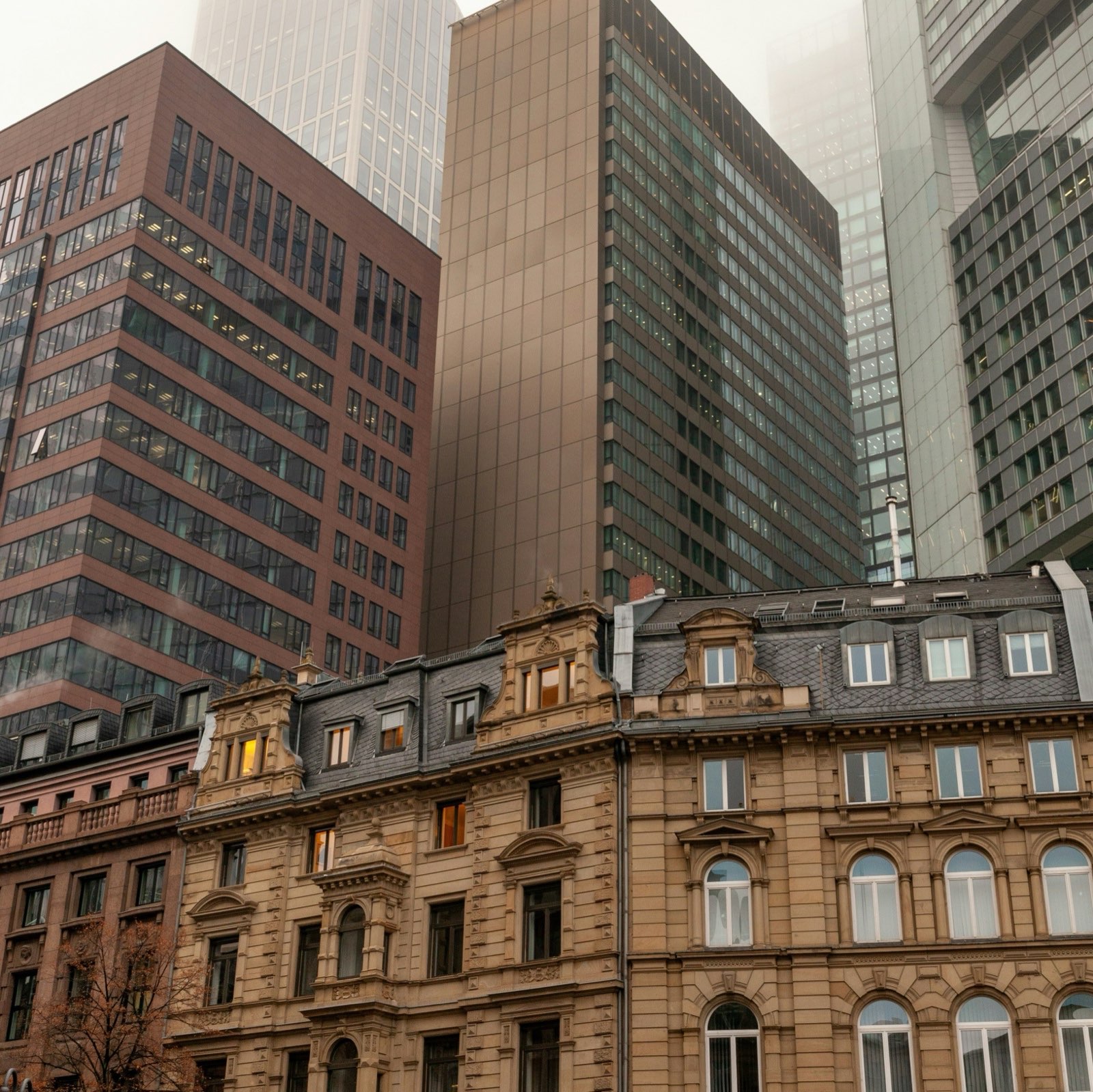 Office towers rising into low cloud above period facades