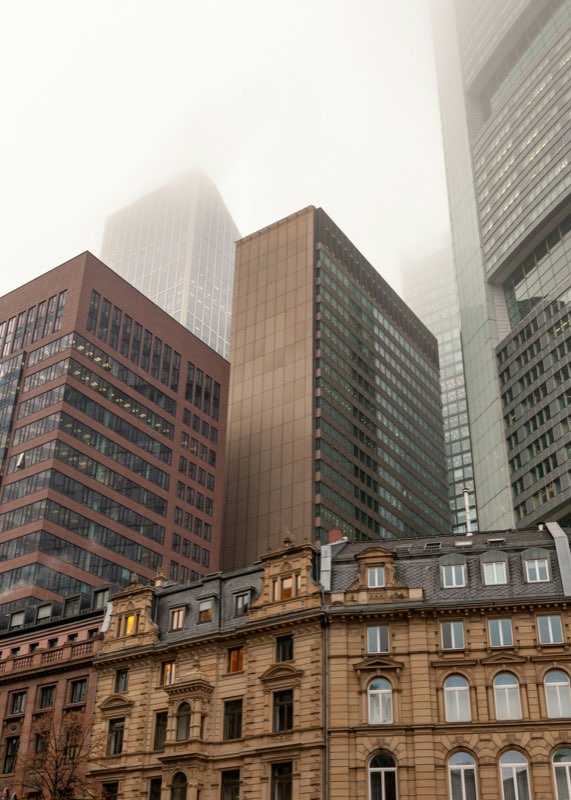 Office towers rising into low cloud above period facades