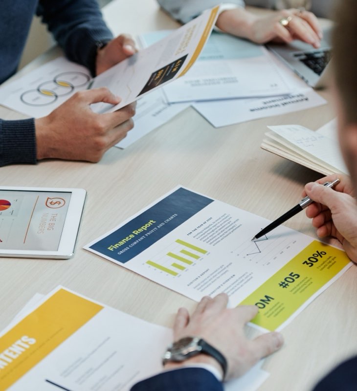 Finance reports and charts spread across a boardroom table