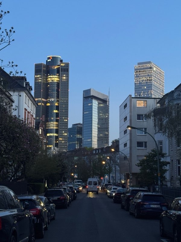 Lit financial towers above a quiet residential street at dusk